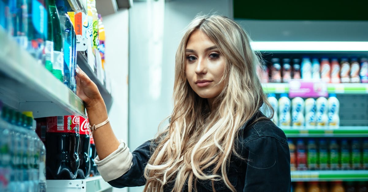 UK Supermarket Deals - Young woman choosing drinks in a brightly lit supermarket aisle.