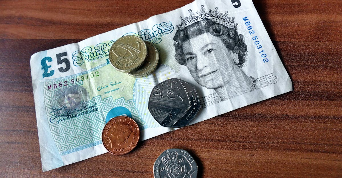 Budgeting - Close-up of a five-pound note and coins representing UK currency on a wooden surface.