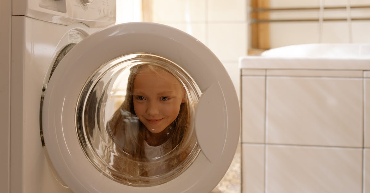 Eco-Friendly Household Saving Tips - A young girl looks curiously into the washing machine door in a bright, modern bathroom.
