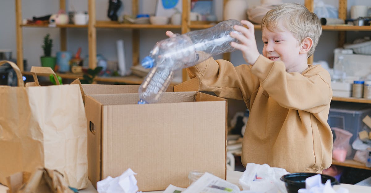 Monetising Household Waste - A young boy happily sorts plastic bottles into a cardboard box for recycling.