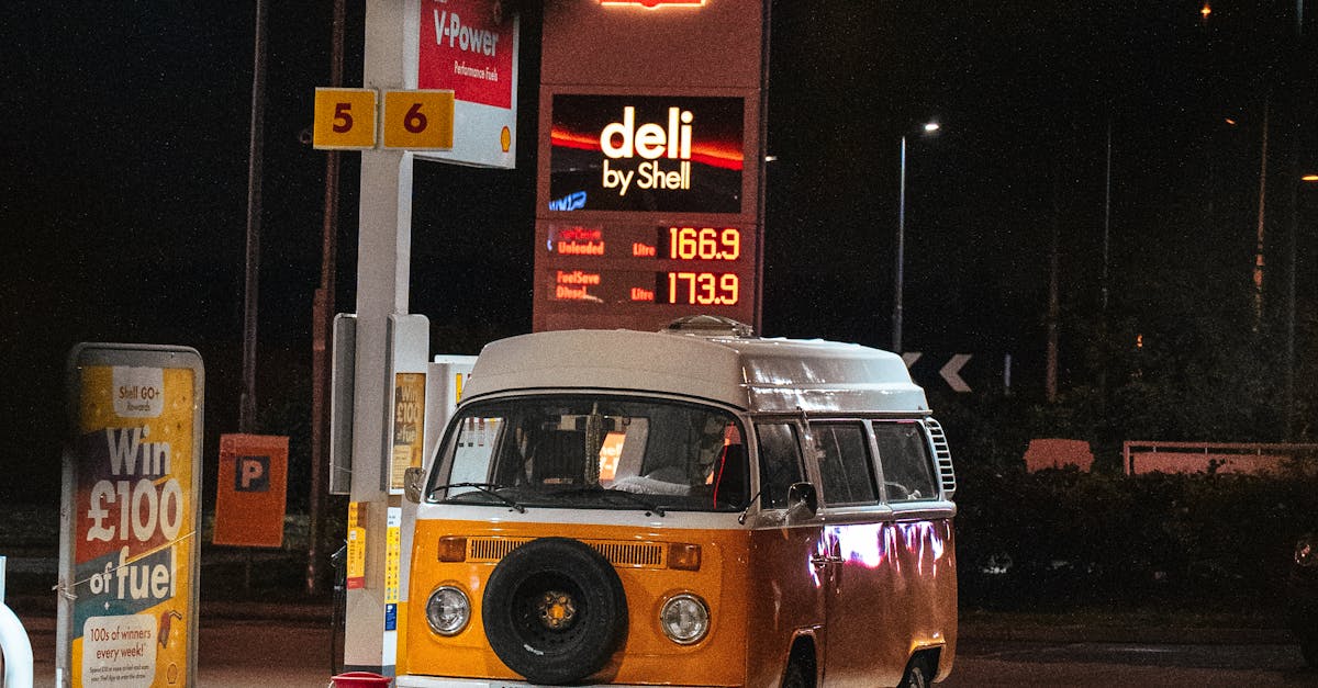 Cheap airline tickets UK - Vintage orange VW camper parked at a brightly lit Shell gas station at night.