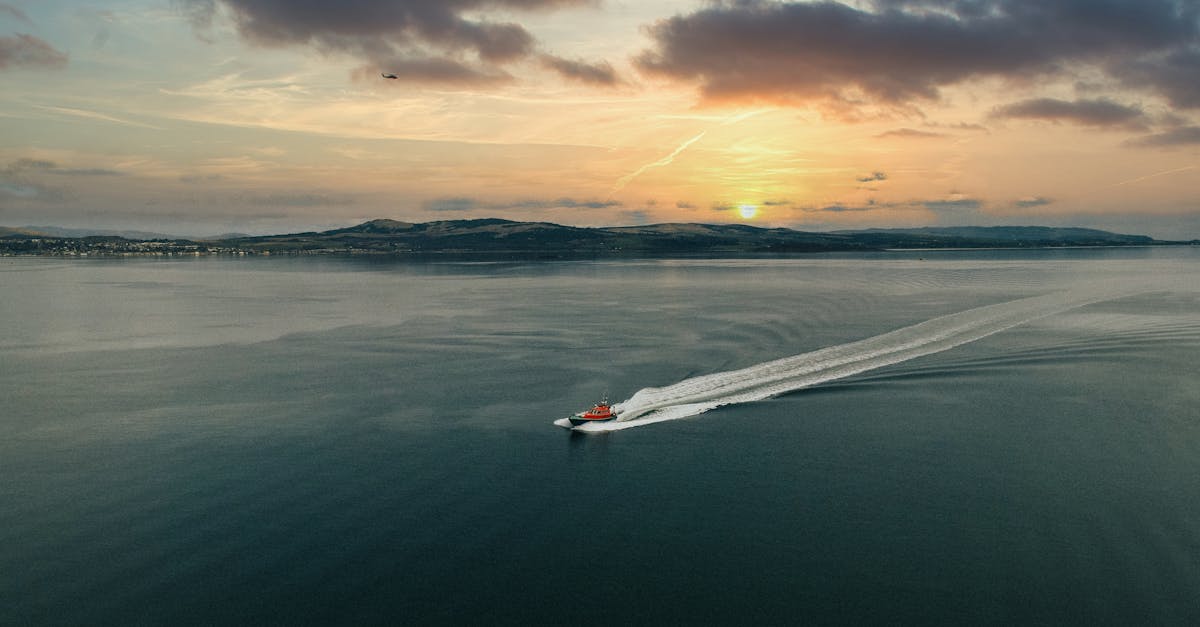 Affordable ferry travel in the UK - A boat swiftly traverses the serene waters at sunset near Greenock, Scotland, under a dramatic sky.