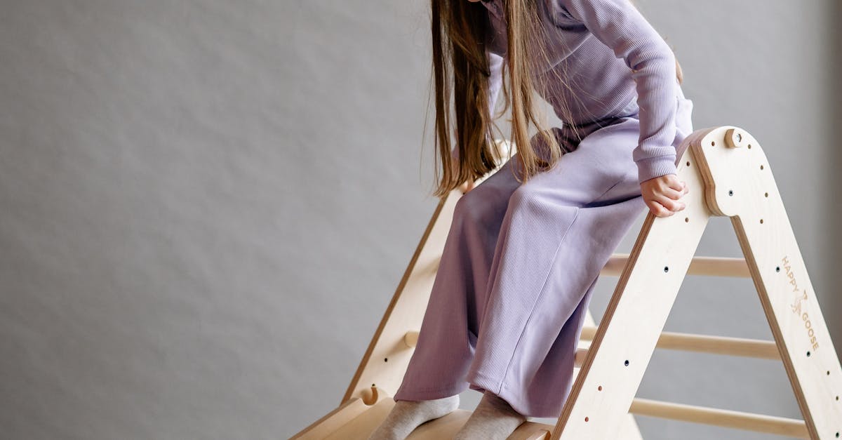 Frugal Family Living - Young girl having fun on a wooden slide indoors.