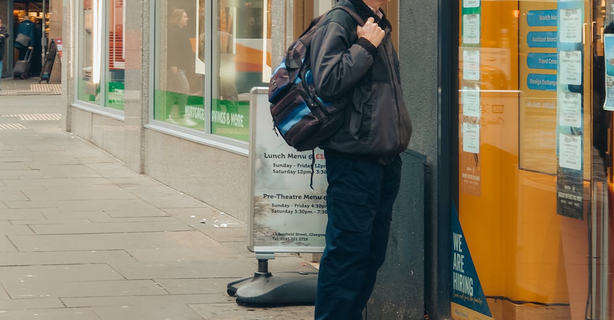 End-of-Season Sales - A man in a coat looks at a store window display on a busy urban street.