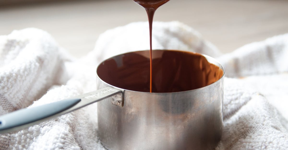 Homemade Takeaway Alternatives - Close-up of melted chocolate dripping from a wooden spoon into a metal pot, creating a sweet and tempting scene.