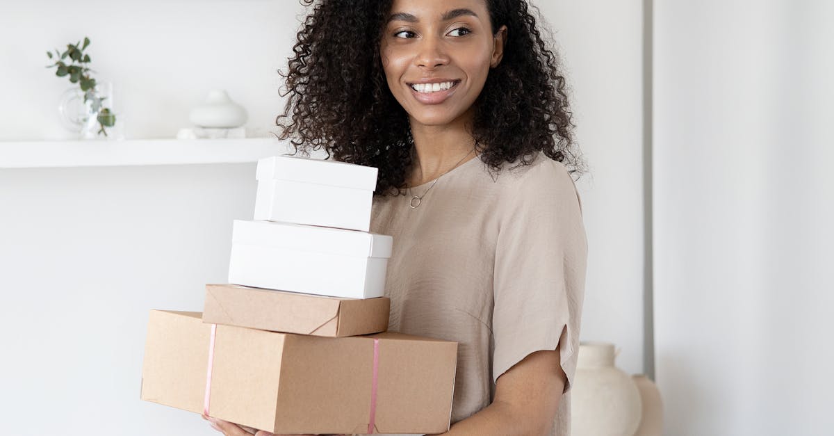 Amazon Marketplace in the UK - Young African American woman smiling while holding cardboard boxes indoors.