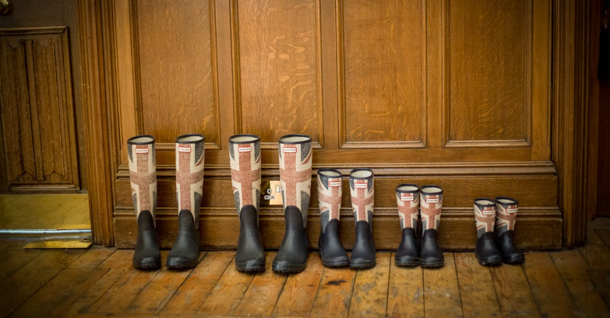 Sustainable Savings - Four pairs of Union Jack wellington boots neatly arranged on a wooden floor indoors.