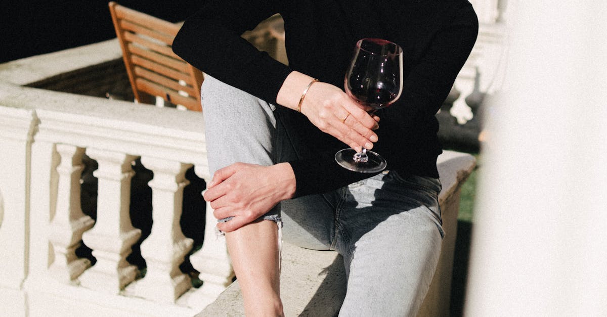Co-living in the UK - Young contemplative female with glass of alcoholic drink looking away from balcony fence in town