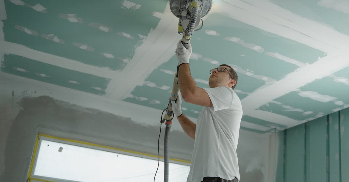 DIY home improvement UK - A professional worker sanding the ceiling during a home renovation project. Indoor construction setting.