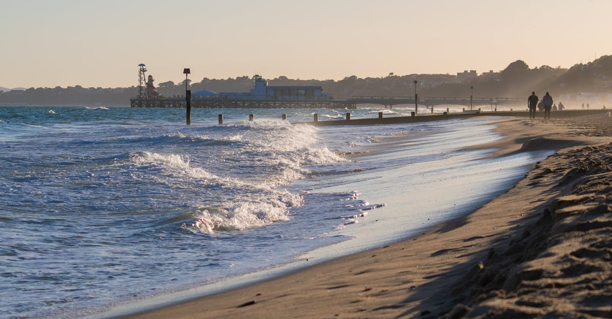 Beachcombing in the UK - Serene Bournemouth beach view at sunset with waves, people, and pier.
