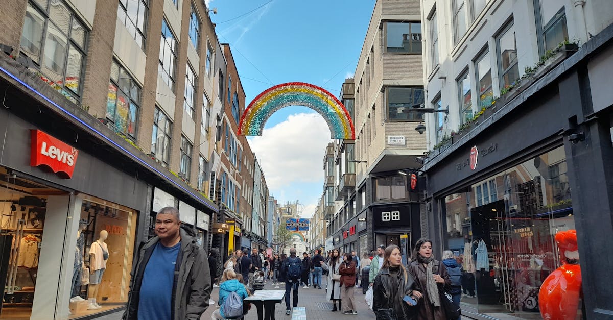 Navigating sale events in the UK - A bustling urban street with shops and a colorful rainbow decoration under a bright blue sky.