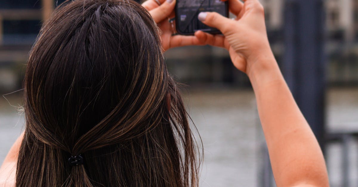 Freelance Photography in the UK - A woman captures London's urban landscape with her smartphone beside the river.