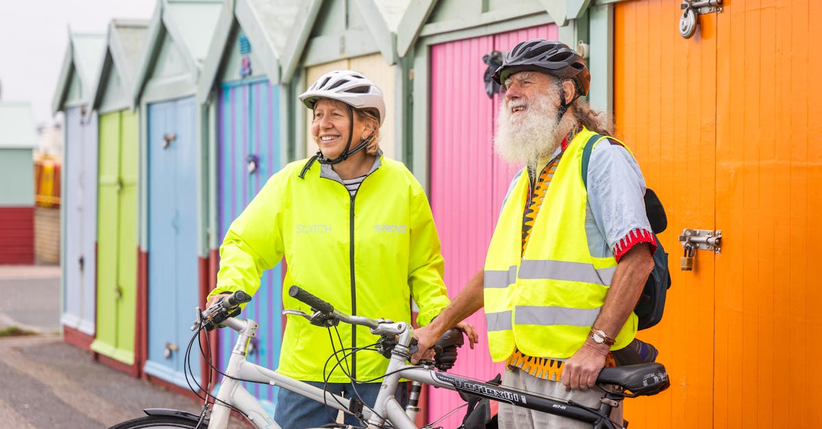 UK Annuities - Senior couple enjoys cycling near vibrant coastal beach huts on a sunny day.