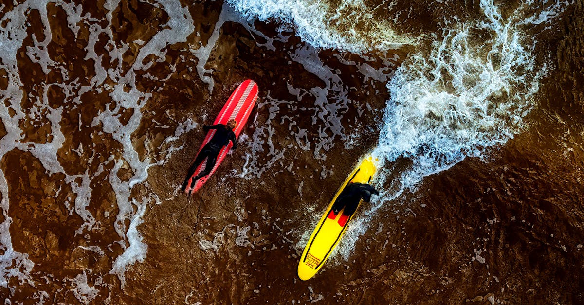 Reselling Surfboards - Aerial view of surfers riding waves at Exmouth Beach, UK, showcasing vibrant surfboards and dynamic ocean motion.
