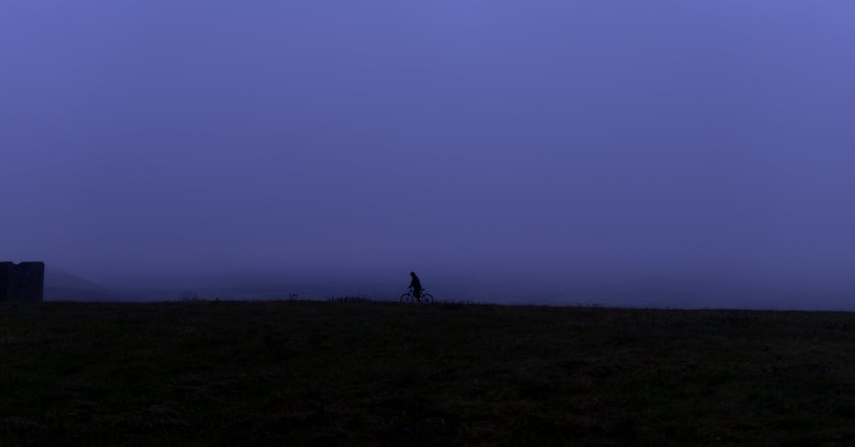 budget fitness UK - A lone cyclist rides in silhouette against a foggy, twilight sky, creating a mysterious and serene outdoor scene.