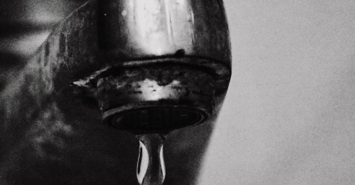 Water-Saving Tips - Minimalist black and white photo of a drop of water hanging from a faucet.